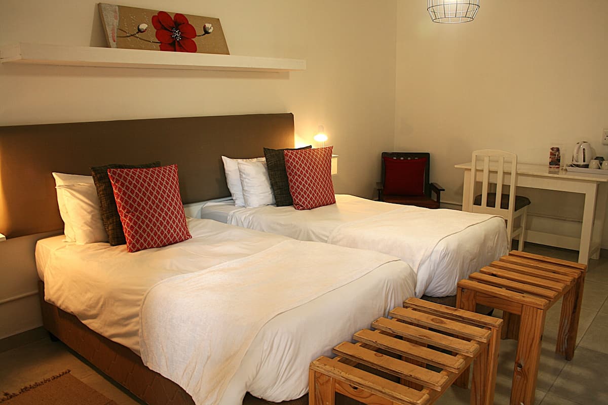 Habitación de hotel con dos camas, un escritorio y una silla.