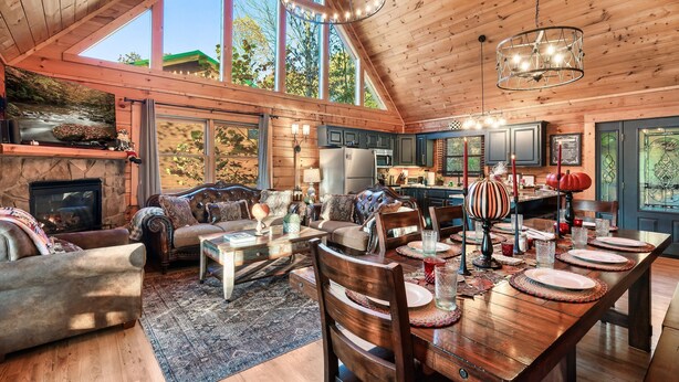 A spacious living room with a fireplace, large windows, and a high ceiling. - Smoky Mountain Ridge Retreat / Panoramic Views • Hot Tub • Game Room & Balconies (Gatlinburg)