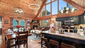 A spacious cabin interior with a large dining area, wooden ceiling, and a kitchen with modern appliances. - Smoky Mountain Ridge Retreat / Panoramic Views • Hot Tub • Game Room & Balconies (Gatlinburg)