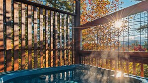 A hot tub with a wooden deck and a view of autumn foliage. - Smoky Mountain Ridge Retreat / Panoramic Views • Hot Tub • Game Room & Balconies (Gatlinburg)