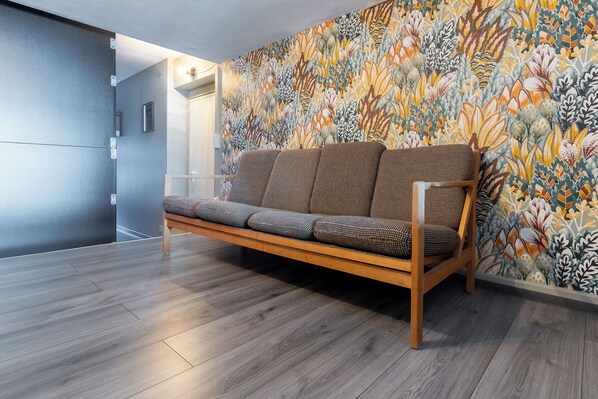 Contemporary living space with a sofa set against a vibrant floral-patterned wall and a sleek door.
