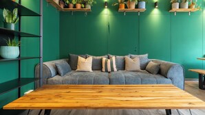 En moderne stue med en grøn væg, en grå sofa og et træbord.