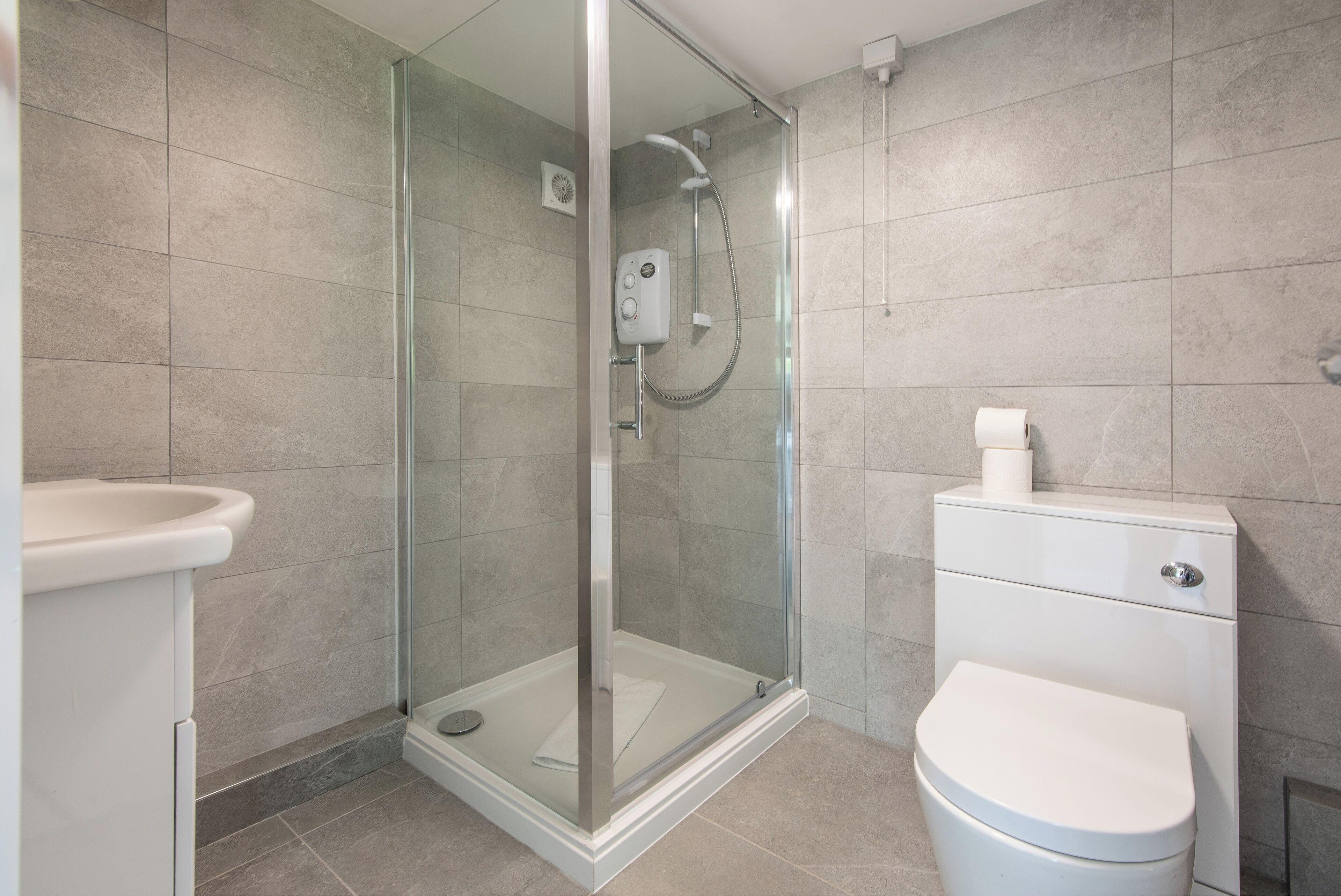 A modern bathroom with a glass-enclosed shower, a white toilet, and a sink.