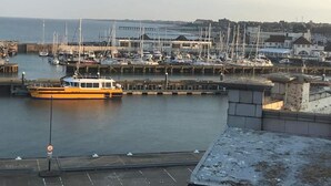 Een jachthaven met aangemeerde boten, een gele boot op de voorgrond en gebouwen op de achtergrond.