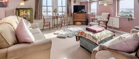 A spacious loft bedroom with skylights, a large window, a television, and a cozy seating area.