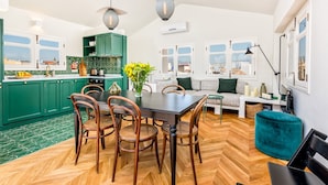 A modern kitchen with green cabinets, a dining table with chairs, and a view of the city through large windows. - Solaga - Sagrado Corazon (Málaga)