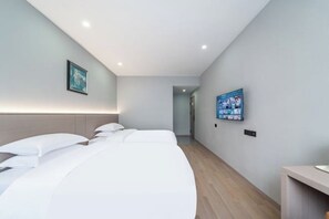 Habitación de hotel con cama, televisión montada en la pared y suelo de madera.