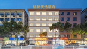 Um edifício de hotel com vários andares, uma placa chamativa e algumas lojas no térreo.
