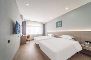 Habitación de hotel con dos camas, un escritorio, una silla, una ventana con cortinas y un cuadro en la pared.
