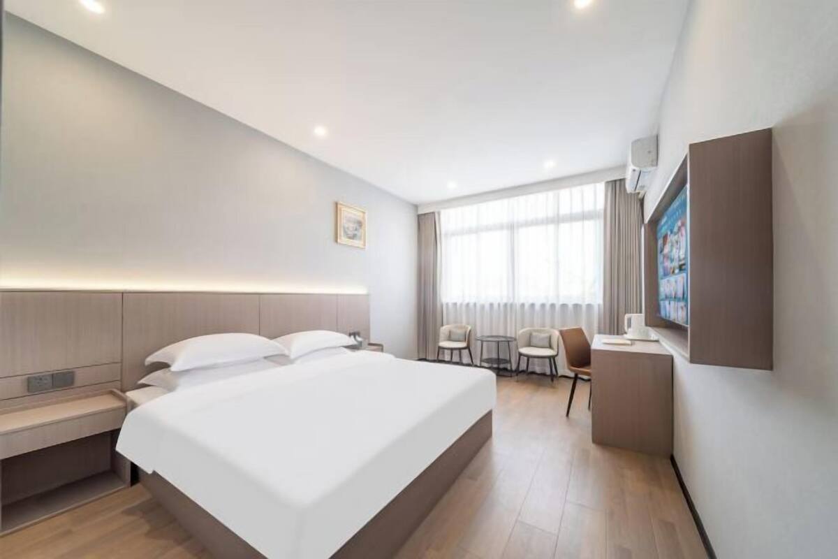 A modern hotel room with a large bed, a desk, and a seating area.