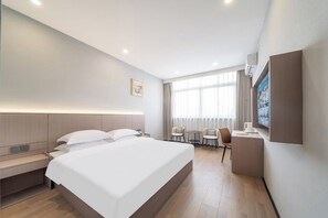 Una habitación de hotel moderna con una cama grande, un escritorio y un espacio de descanso.