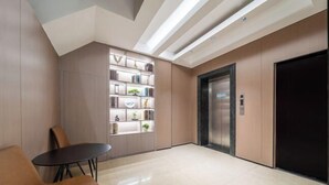 Um lobby moderno com área de estar central, estante embutida e elevador.