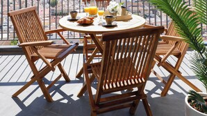 A balcony with a round table, wooden chairs, a hanging light fixture, and a potted plant. - Flat like in a skyscraper in Manhattan , but with views of old Malaga Urban Sky (Malaga)