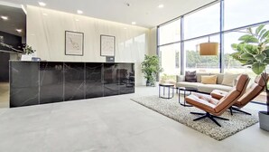 A modern reception area with a marble reception desk, framed artwork, and a seating area with a sofa and chairs. - Flat like in a skyscraper in Manhattan , but with views of old Malaga Urban Sky (Malaga)