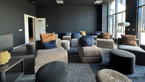 A modern lounge area with multiple seating options, a door labeled "CINE," and large windows allowing natural light. - Flat like in a skyscraper in Manhattan , but with views of old Malaga Urban Sky (Malaga)