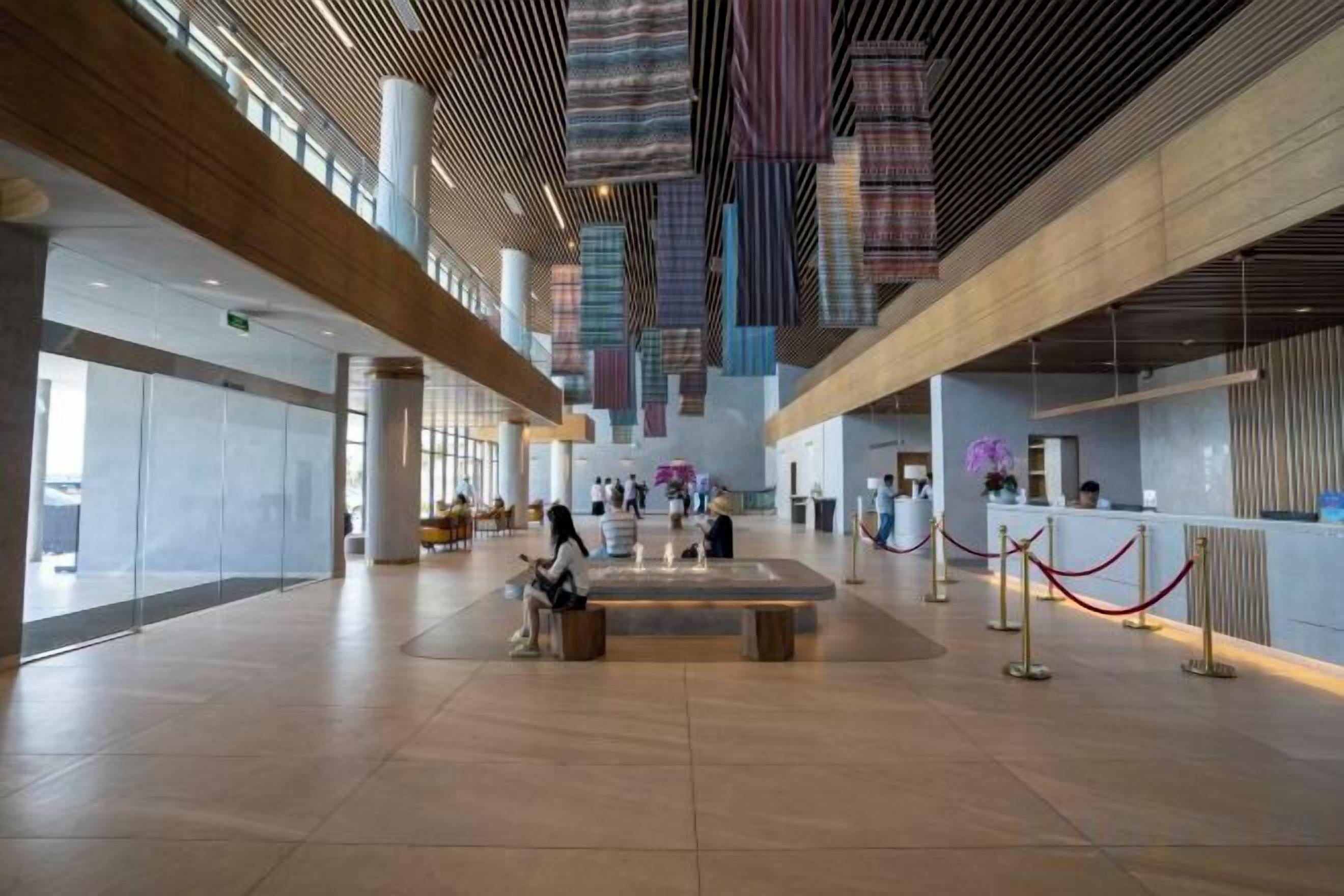 A spacious lobby with a high ceiling, a reception desk, and a seating area.