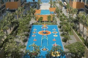 An aerial view of a resort with a pool area, palm trees, and a clear sky. - Mandala Cham Bay Mui Ne (Phan Thiet)