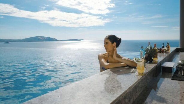 A person relaxing by a pool with a view of the sea and distant islands. - Mandala Cham Bay Mui Ne (Phan Thiet)