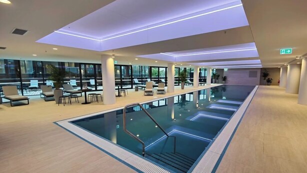 Ein moderner, überdachter Pool mit Liegebereichen und großen Fenstern.