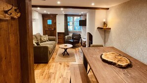 A cozy living room with a wooden floor, a sofa, a coffee table, and a dining table with a unique centerpiece.