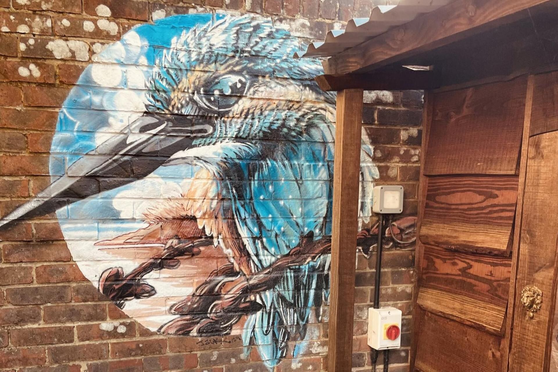 A mural of a bird on a brick wall.