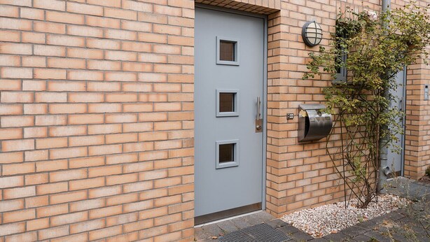 A modern building with a grey door, a small window, and a mailbox on the brick wall. - Anubis_relaxed&stay! Stylish short-term accommodation in leafy Hamburg-Niendorf (Hamburg)
