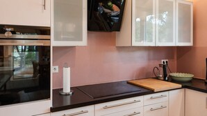 A modern kitchen with white cabinets, a black countertop, and a wooden cutting board. - Anubis_relaxed&stay! Stylish short-term accommodation in leafy Hamburg-Niendorf (Hamburg)