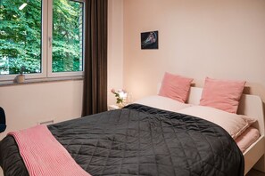 A bedroom with a bed, a nightstand, a window with curtains, and a wall-mounted picture. - Anubis_relaxed&stay! Stylish short-term accommodation in leafy Hamburg-Niendorf (Hamburg)