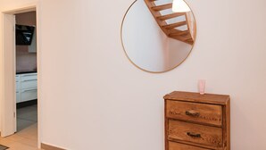A room with a wooden dresser, a round mirror, and a small table with a bottle. - Anubis_relaxed&stay! Stylish short-term accommodation in leafy Hamburg-Niendorf (Hamburg)