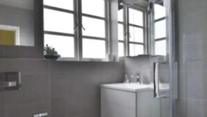 A modern bathroom with a toilet, sink, and shower area. - Luxury Central Hale Living (Altrincham)