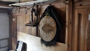 Tunnelmallinen, maalaishenkinen sisustus, jossa on puuseinät, punottu kori ja pieni hylly koriste-esineitä varten.