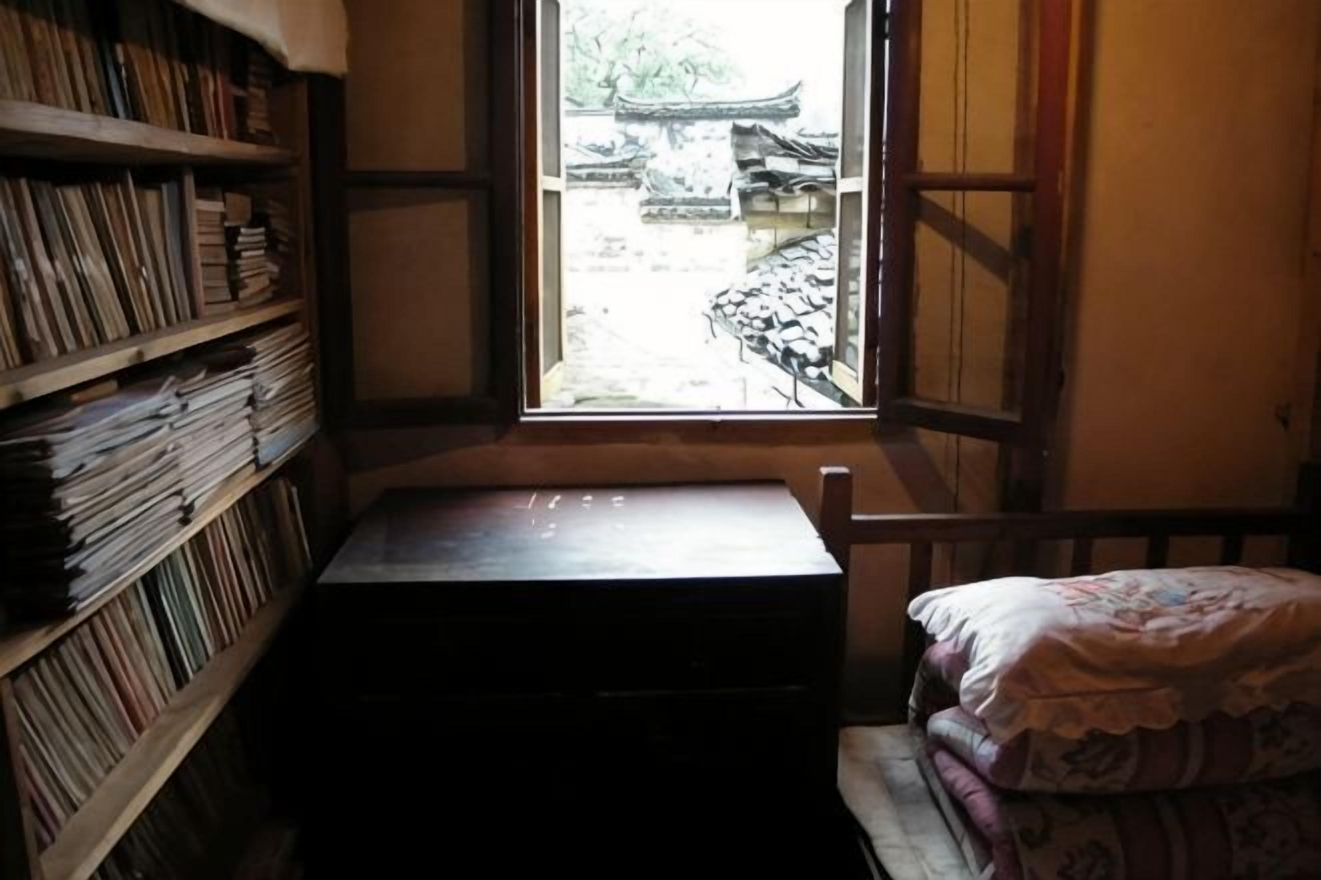 A room with a window, a wooden desk, and a bed.