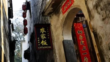 A narrow alleyway with traditional architecture, including an arched doorway and hanging red lanterns.