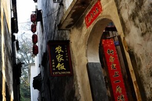 A narrow alleyway with traditional architecture, including an arched doorway and hanging red lanterns. - Wuyuan Xiaoqi Wangyuanheng Laoshi Gujing Yizhan (Wuyuan)