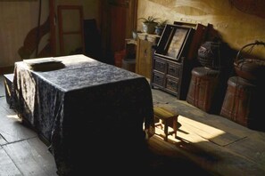 A room with a table covered by a tablecloth, a wooden cabinet, and a chair. - Wuyuan Xiaoqi Wangyuanheng Laoshi Gujing Yizhan (Wuyuan)