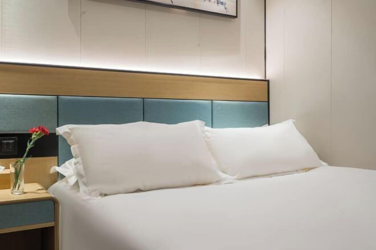A hotel room with a bed, a nightstand, and a wall-mounted artwork.
