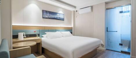 Habitació d'hotel amb un llit, zona de seients, espai per al cafè i un quadre penjat a la paret.