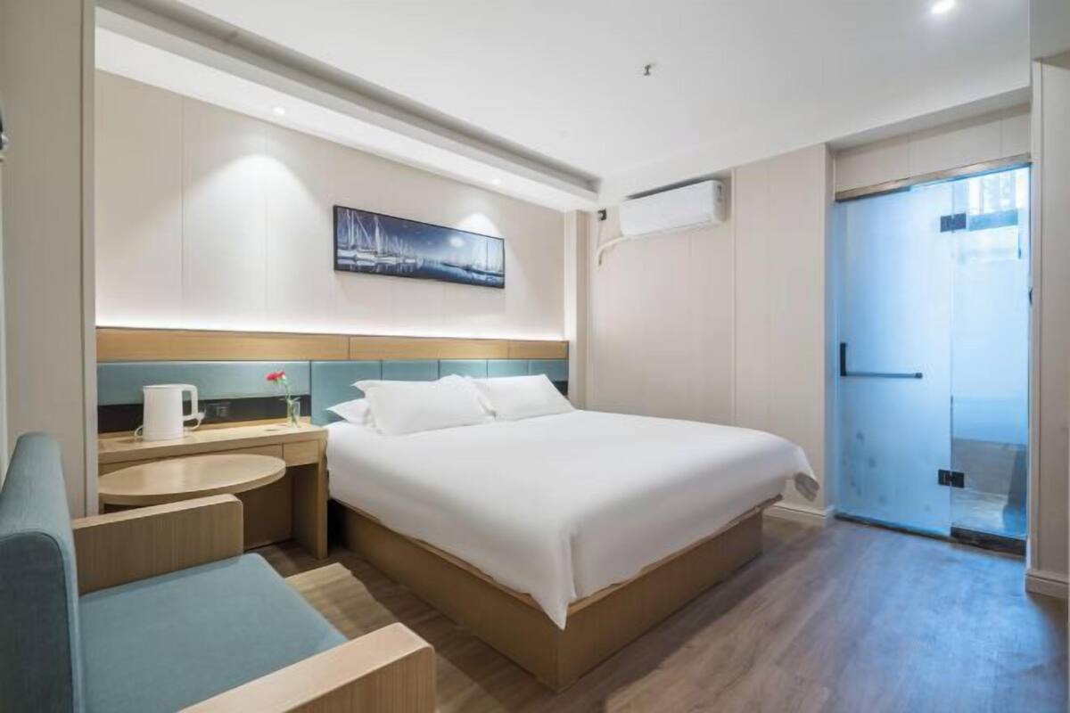 Ein modernes Hotelzimmer mit einem großen Bett, einem Nachttisch, einem Sessel und einem Gemälde an der Wand.
