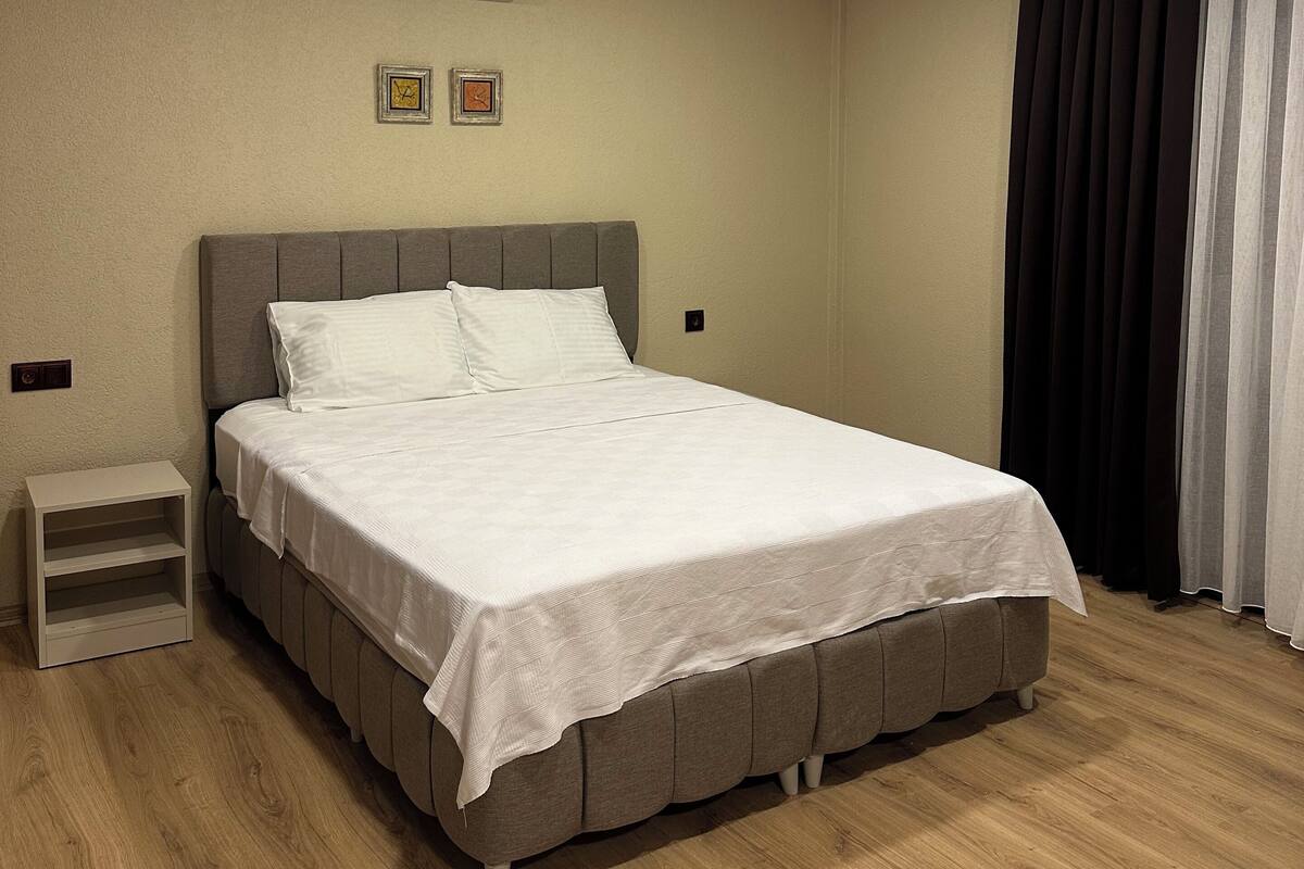 Un dormitorio ordenado con cama, mesitas de noche y un equipo de aire acondicionado en la pared.