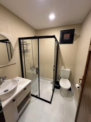 Un baño con ducha de vidrio, lavamanos, inodoro y espejo.