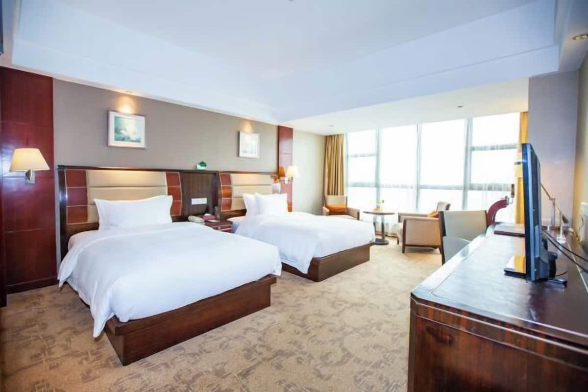 Une chambre d’hôtel avec deux lits, un bureau, une chaise et un téléviseur.