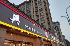 A building facade with a prominent sign, a storefront with illuminated signage, and a street lamp.