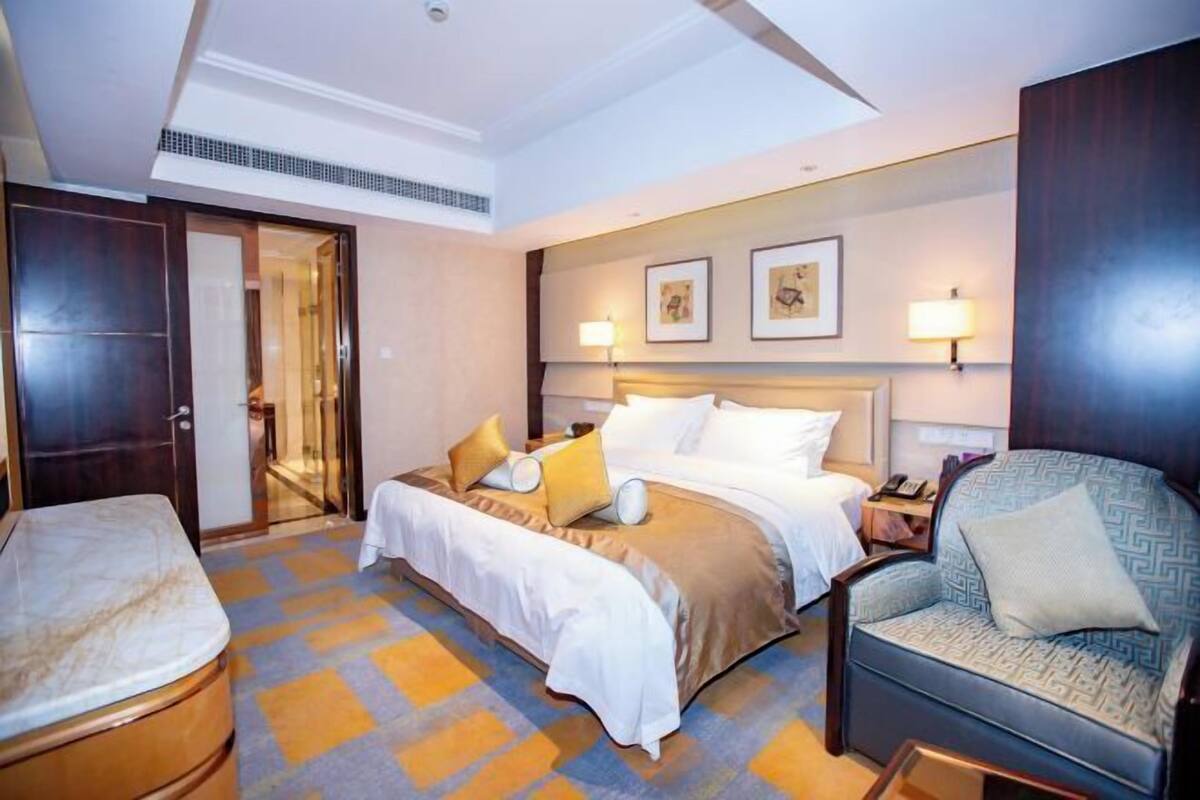 Une chambre d’hôtel avec un lit, une chaise, un bureau et une porte de salle de bain.
