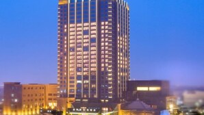 Een hoog hotel met meerdere verdiepingen, een opvallende ingang en omliggende gebouwen.