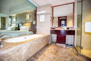 Een moderne hotelbadkamer met een ruime badkuip, een aparte douche en een wastafel met spiegel.