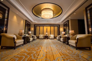 A hotel lobby with a large chandelier, leather armchairs, a patterned carpet, and a large window with a view. - Hangzhou Xinghai Narada Hotel (Hangzhou)