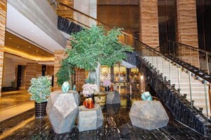 Un vestíbulo con suelo de mármol, una escalera y plantas decorativas.