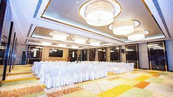 A conference room with rows of white chairs, a patterned carpet, and a chandelier.