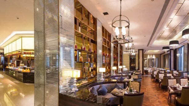 Een moderne hotellobby met een bar, zitplaatsen en een grote spiegelwand.