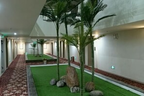 A corridor with artificial grass, palm trees, and rocks. - Jingyuan Business Hotel (Guangzhou)